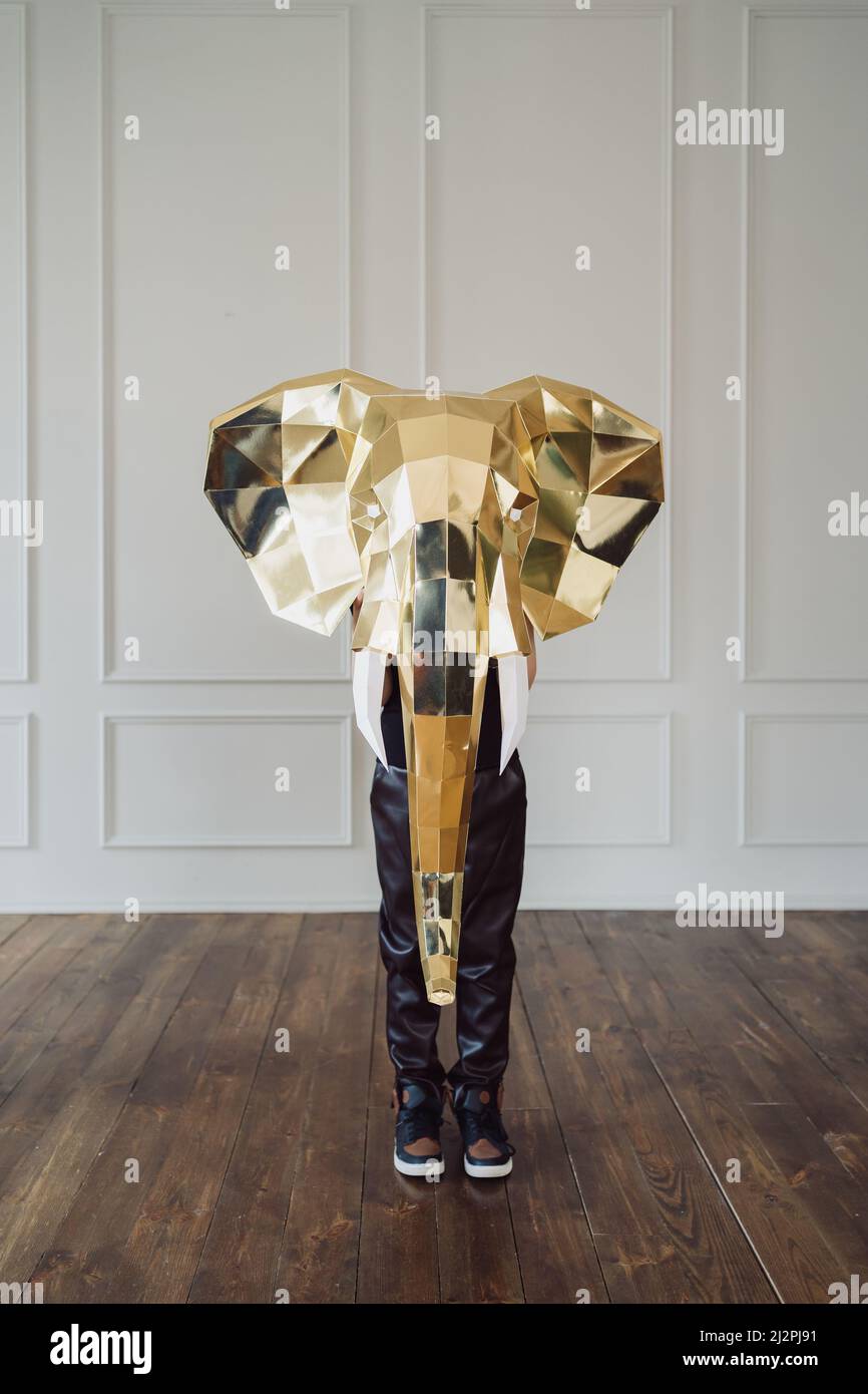 Abstract image, human holding a golden elephant head on a white wall ...