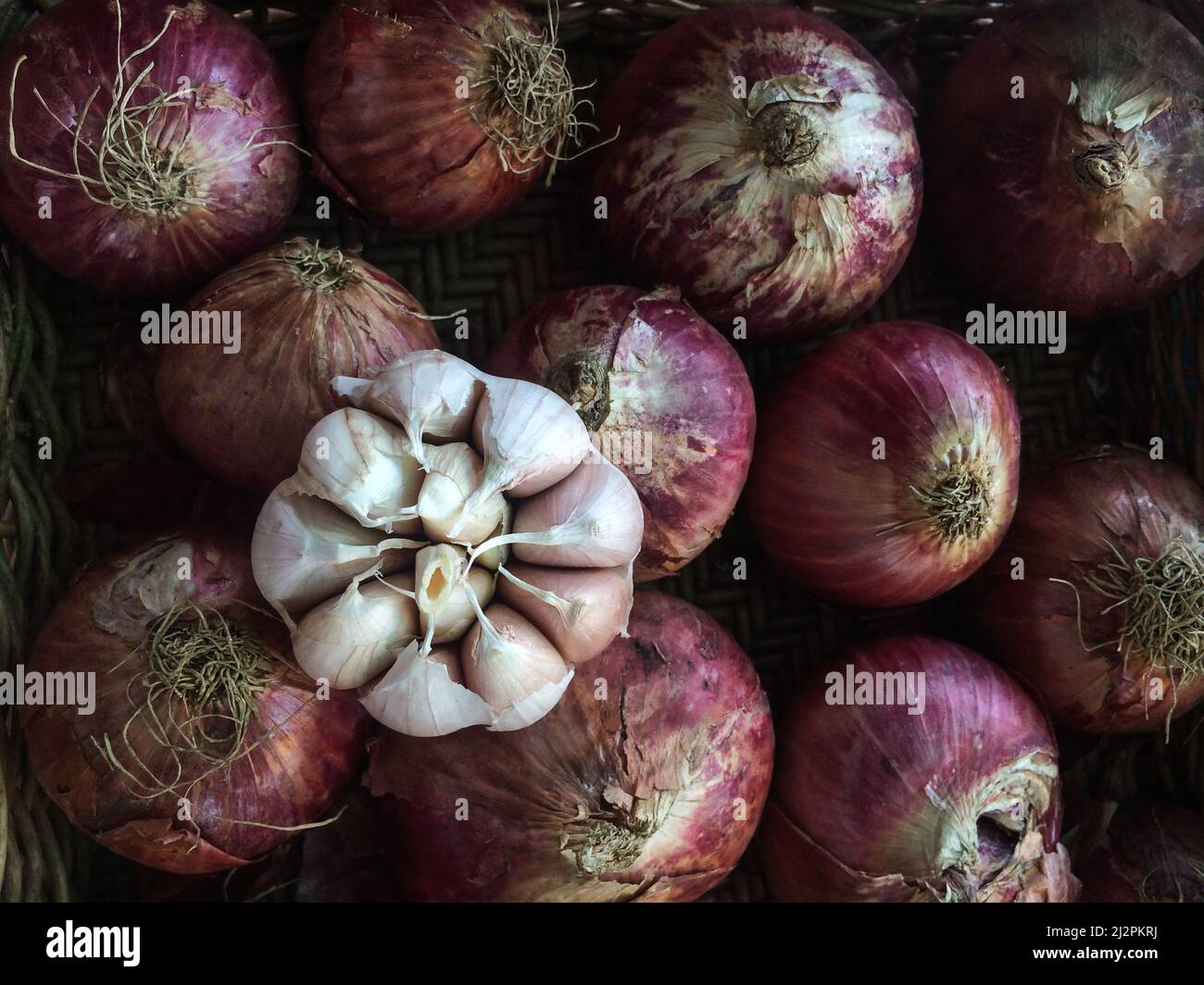 Dry garlic bulb, and red shallot bulbs in a basket for sale at a wet