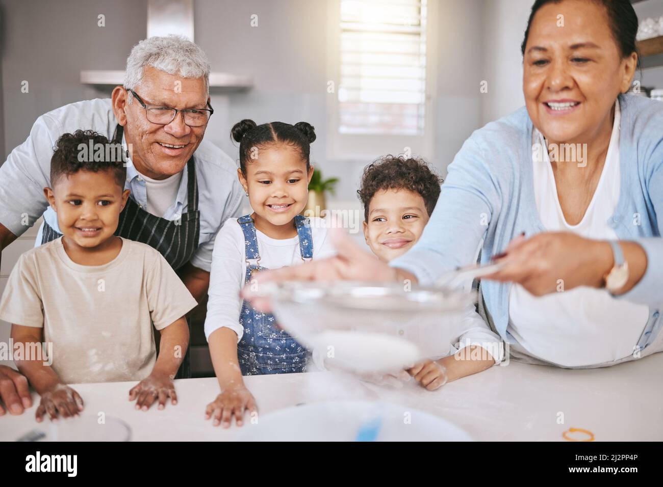 Learning family secrets. Shot of a mature couple baking with their grandkids at home. Stock Photo