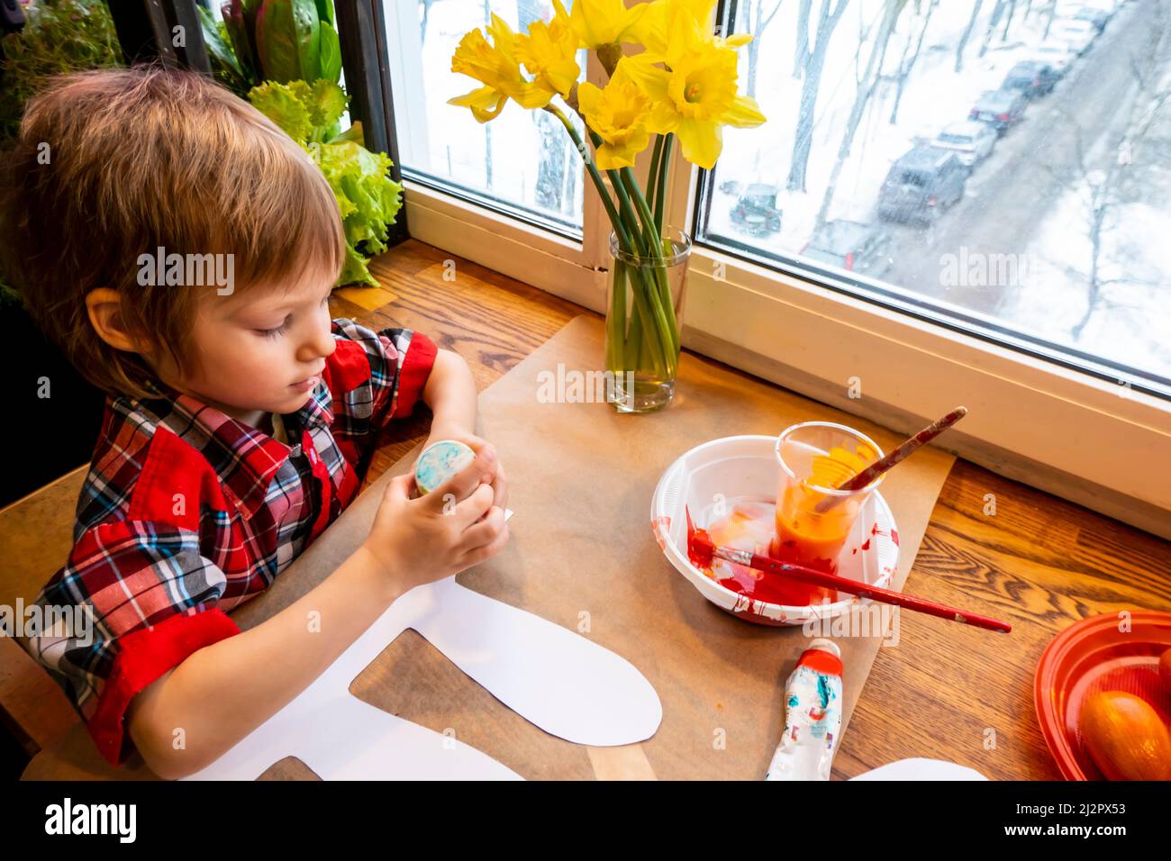 boy drawing the ears of a handmade Easter bunny made of cardboard. Preparation for the celebration of the Easter holiday. Stock Photo