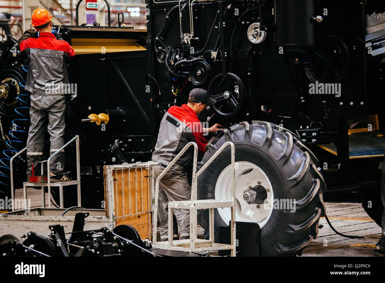 Industrial workers assembles agricultural harvester in workshop. Stock Photo
