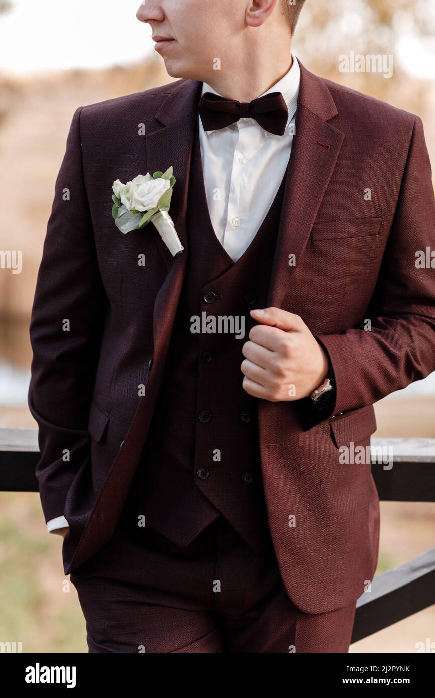 Un evento Ejercicio mañanero Significado the groom in a bordo wedding suit, a tuxedo in a white shirt, bow tie and a  roses buttonhole. High quality photo Stock Photo - Alamy