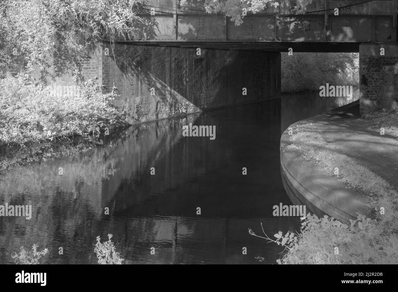 Infrared picture looking under the railway bridge on the Bridgewater and Taunton Canal in Taunton, Somerset, England, UK. part of the East Deane Way. Stock Photo