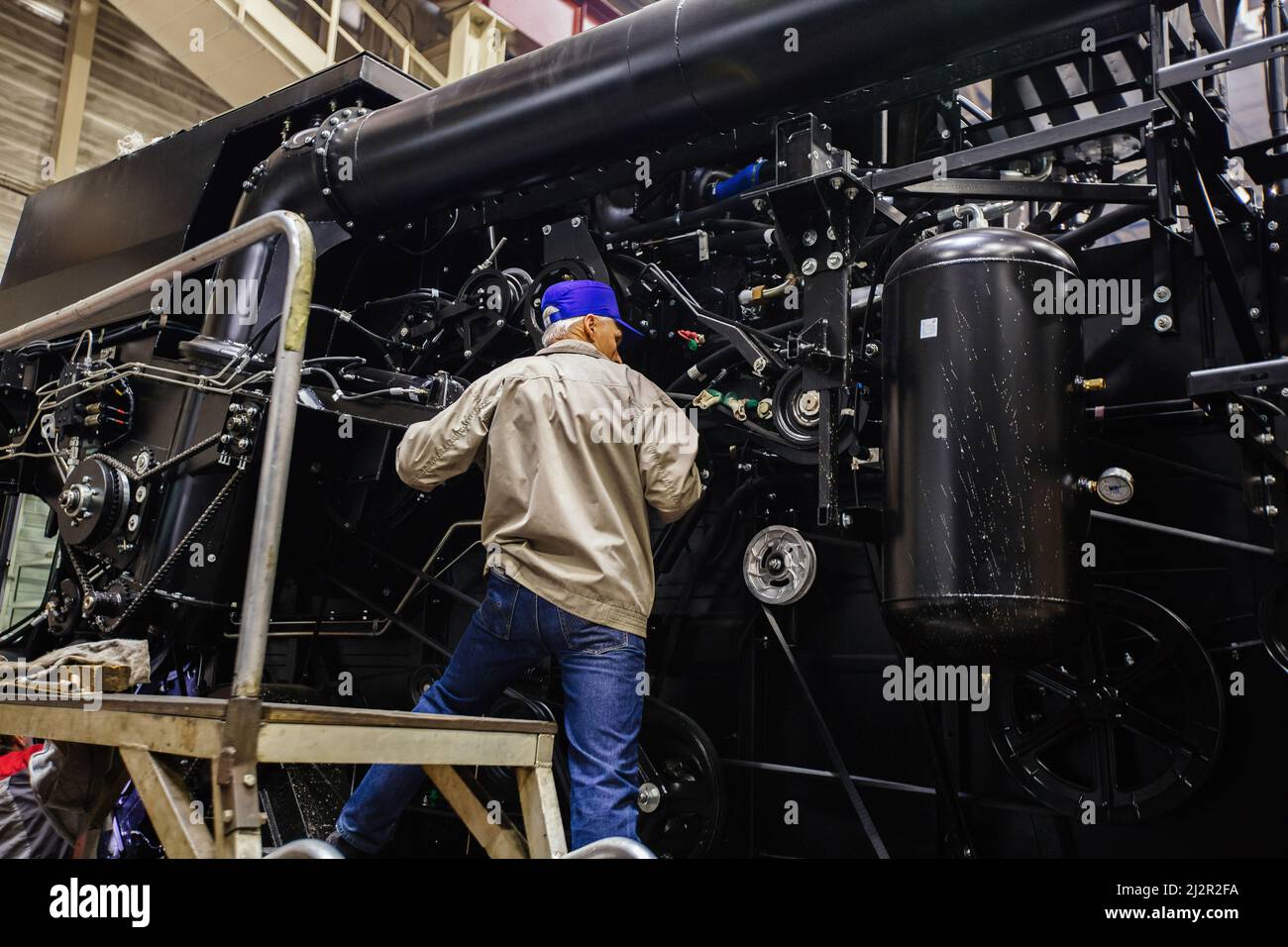 Industrial workers assembles agricultural harvester in workshop. Stock Photo