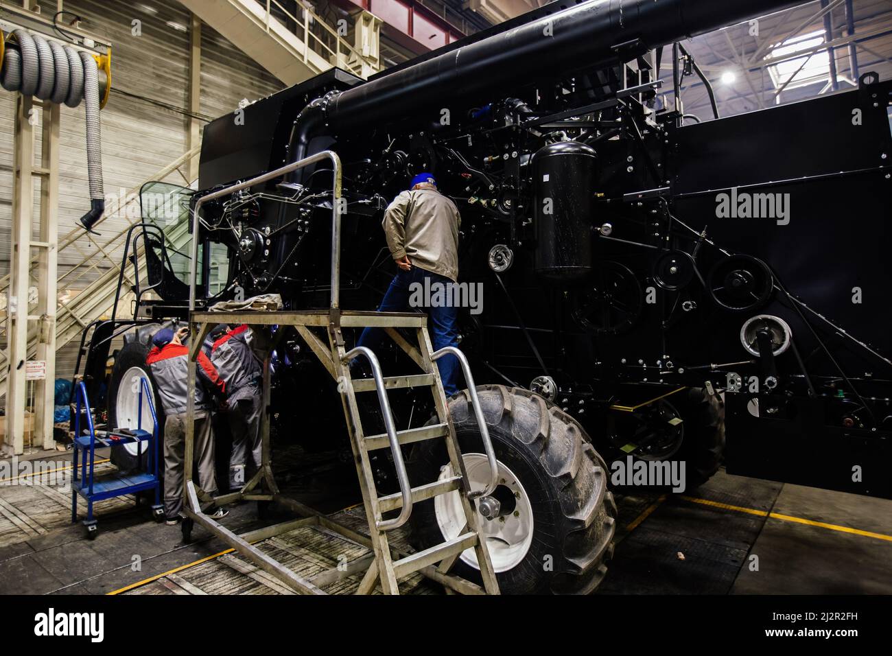 Industrial workers assembles agricultural harvester in workshop. Stock Photo