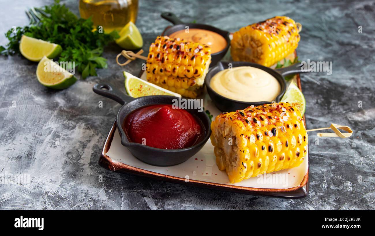 grilled cob corn with spices lime white yellow red sauce close up Stock Photo