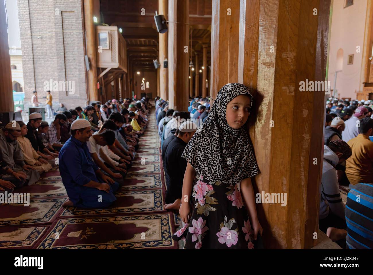April 3, 2022, Srinagar, Jammu and Kashmir, India: A muslim girl looks on as Kashmiri Muslims offer noon prayers on the first day of Ramadan. Islam's holiest month Ramadan is a period of intense prayer, dawn-to-dusk fasting and nightly feasts. (Credit Image: © Idrees Abbas/SOPA Images via ZUMA Press Wire) Stock Photo