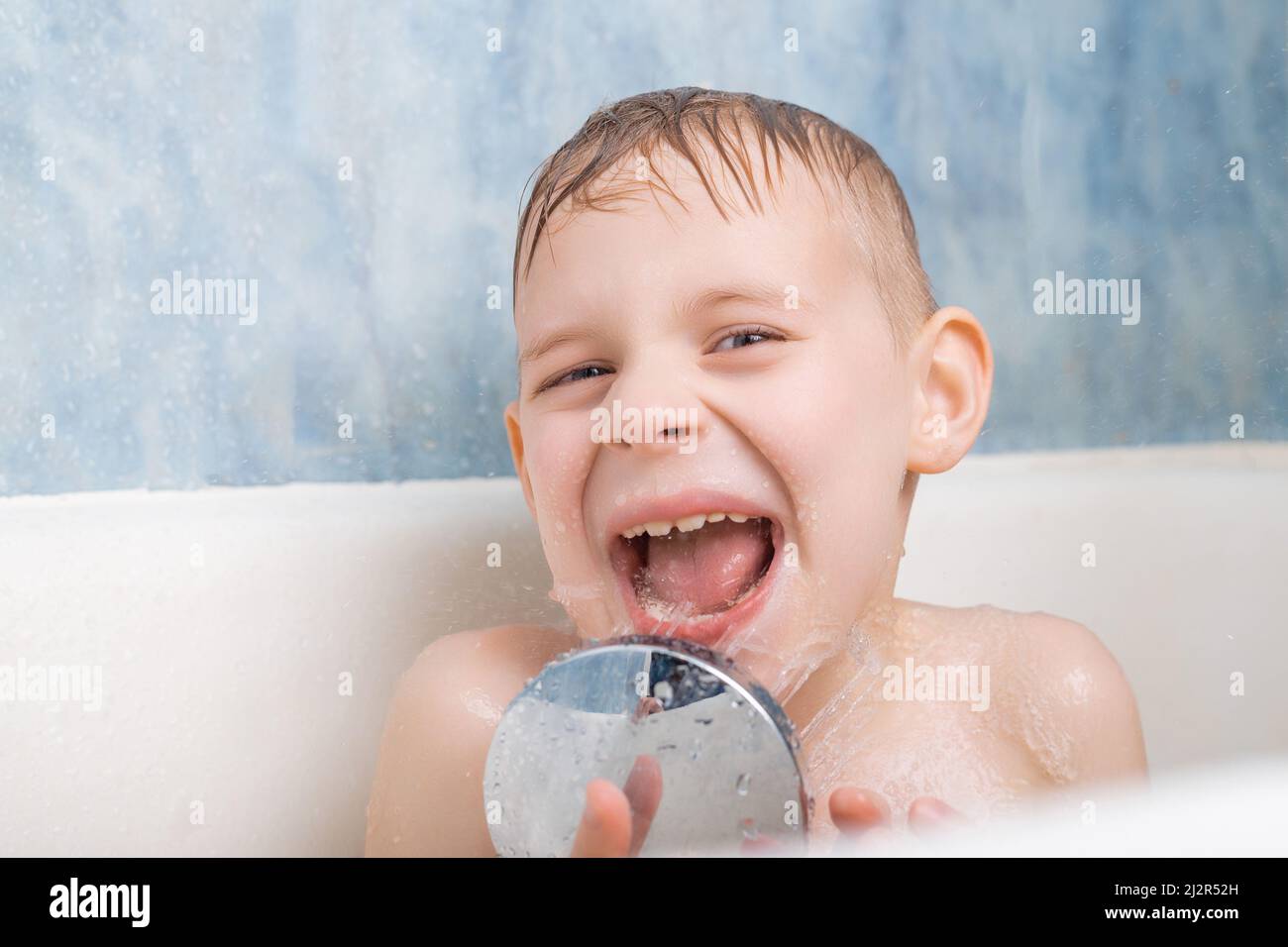 A young boy takes a bath. Played with a shower. The joy, pleasure of