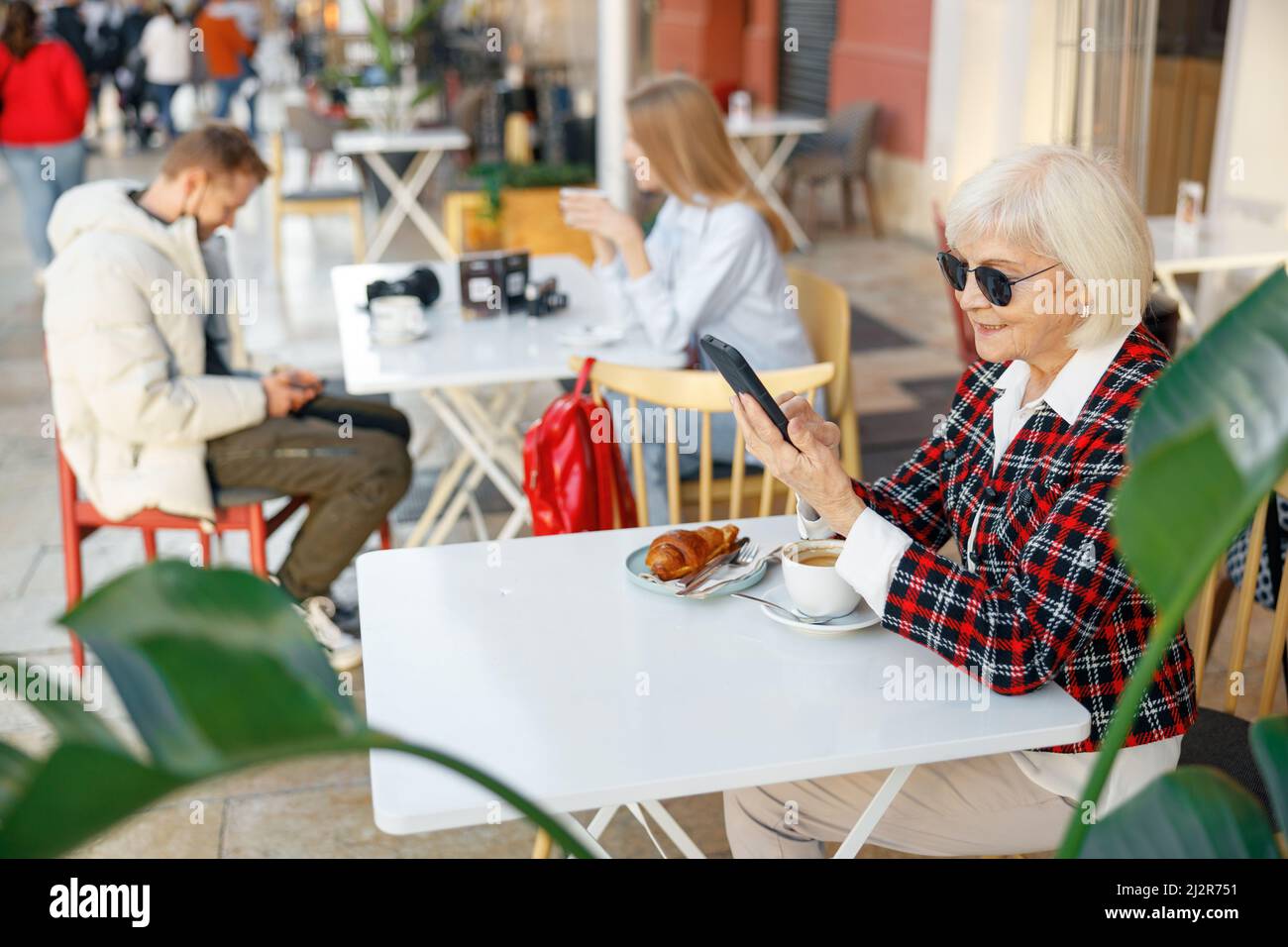 Senior woman using cellphone while having lunch in cafe Stock Photo