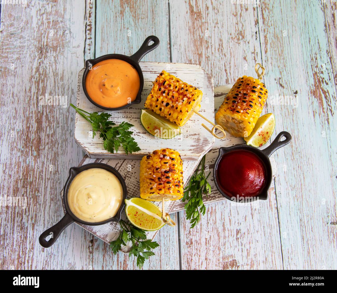grilled cob corn with spices lime white yellow red sauce top view Stock Photo
