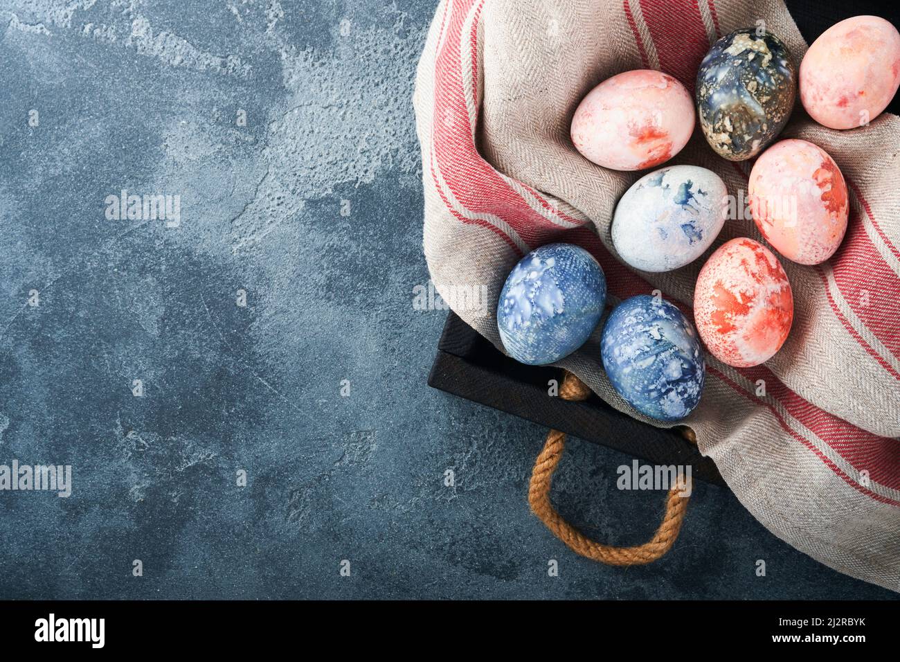 Easter eggs. Dyed Easter eggs with marble stone effect ref and blue color in rustic style on dark stone background. Easter background. Top view. Stock Photo