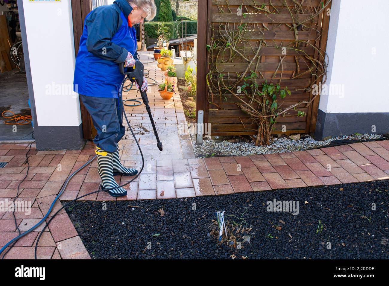 Worker cleaning driveway with gasoline high pressure washer splashing