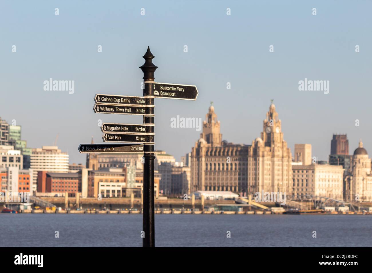Seacombe, UK: Fingerpost sign on Wallasey promenade with river Mersey and waterfront buildings in the background. Stock Photo