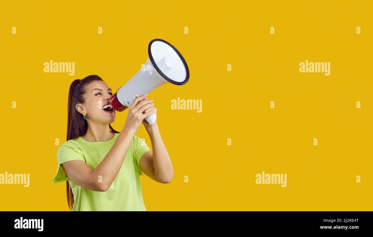 Happy young woman shouting through megaphone and making loud announcement about sale Stock Photo