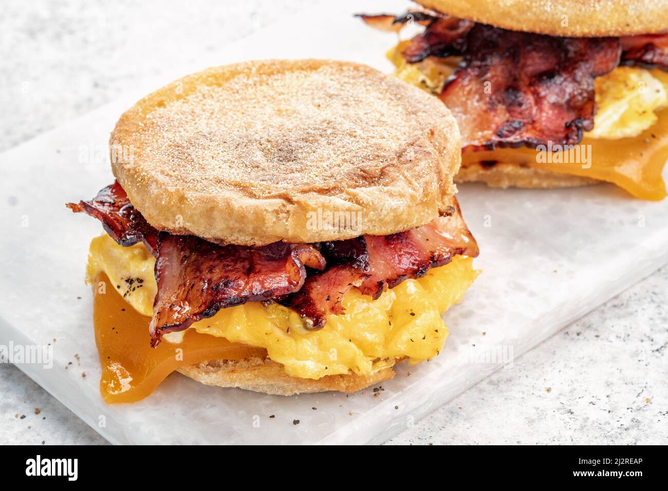 English muffin, egg, ham, and cheese breakfast sandwich on a cutting