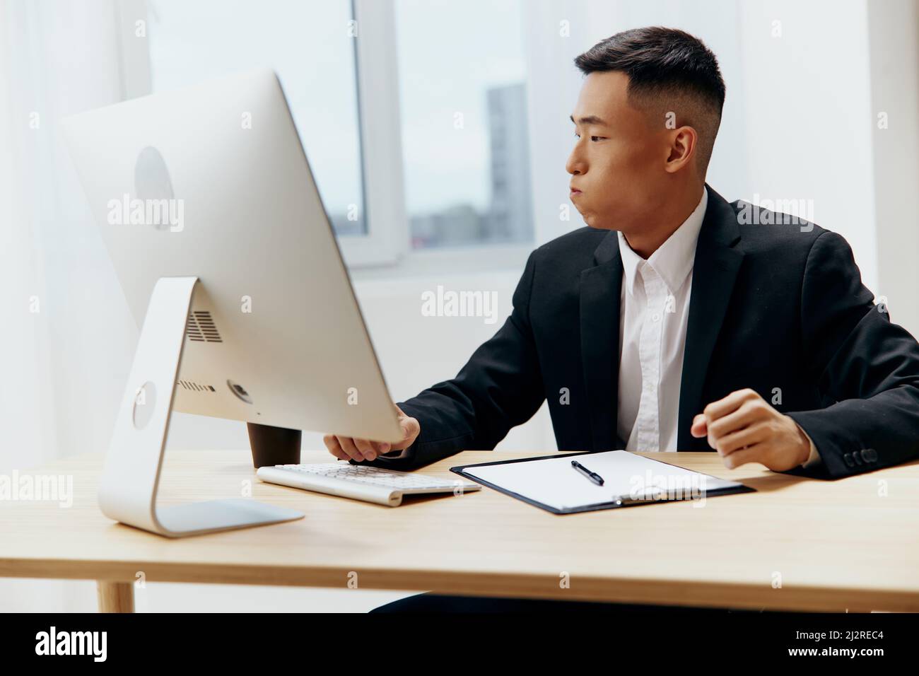 Asian man sitting at a desk in front of a computer Lifestyle Stock ...