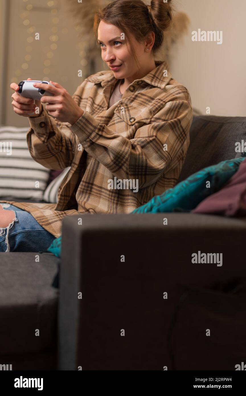 Girl gamer or streamer at home playing a video game. She has a joystick in her hands. Fun hobby, chatting with friends, competition, youth culture, es Stock Photo