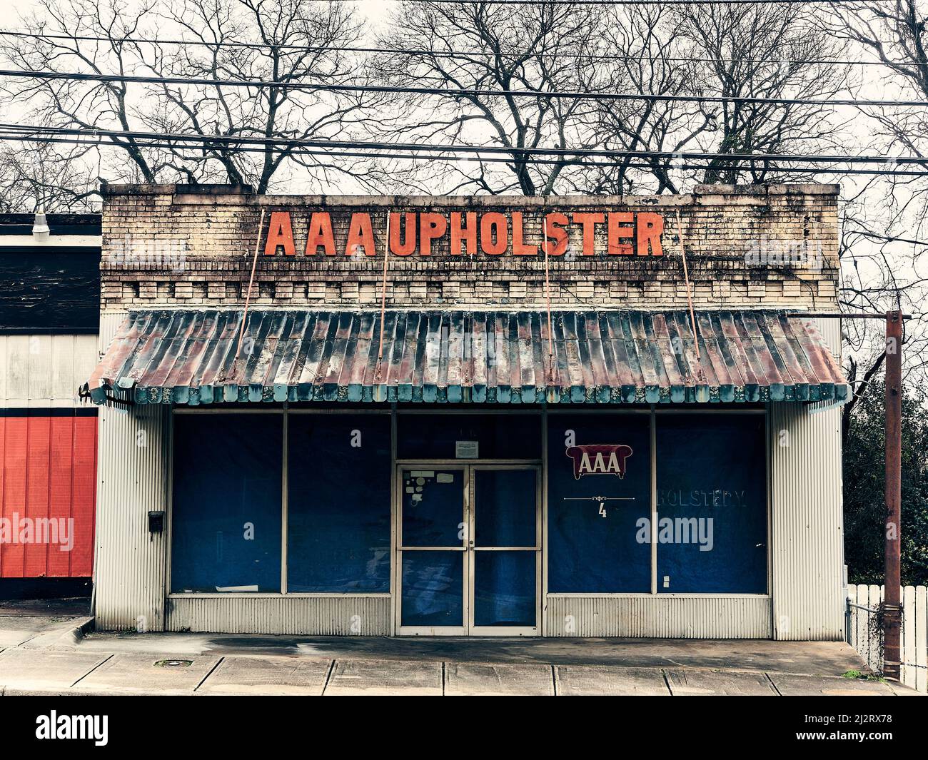 Closed abandoned upholstery store or store front in a poor part of town in Montgomery Alabama, USA. Stock Photo