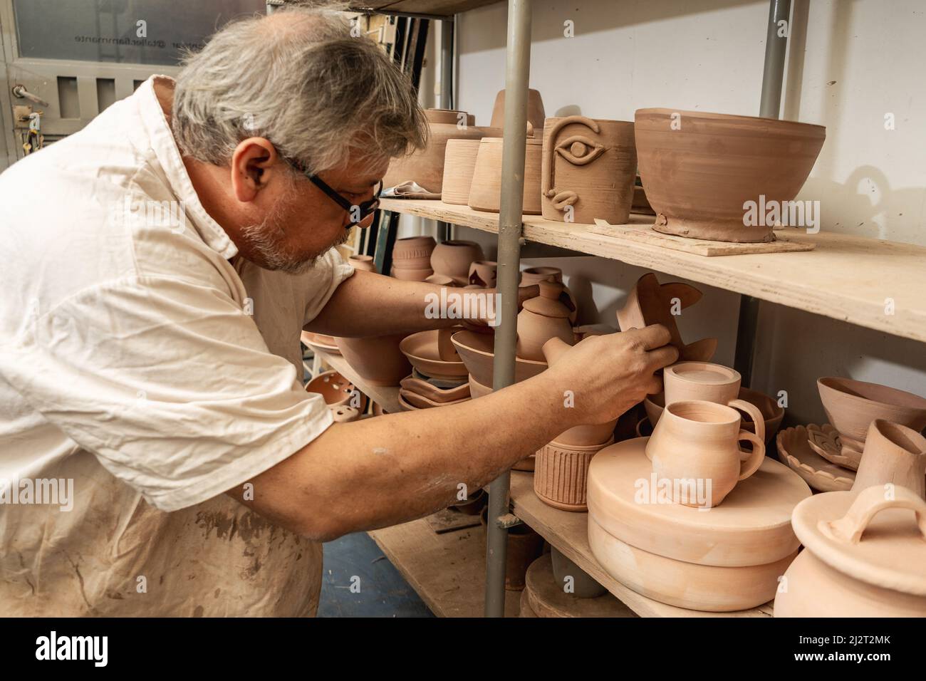 Pottery craftsman checking the pieces and organizing the shelves. Clay