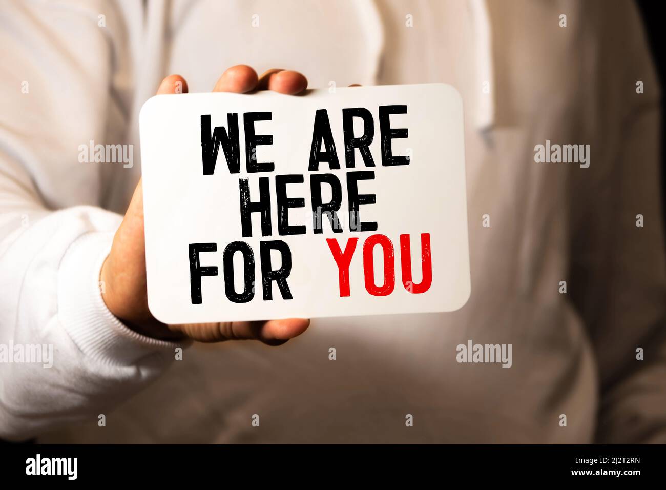 We are here for you handwriting text on paper, on office agenda. Copy ...