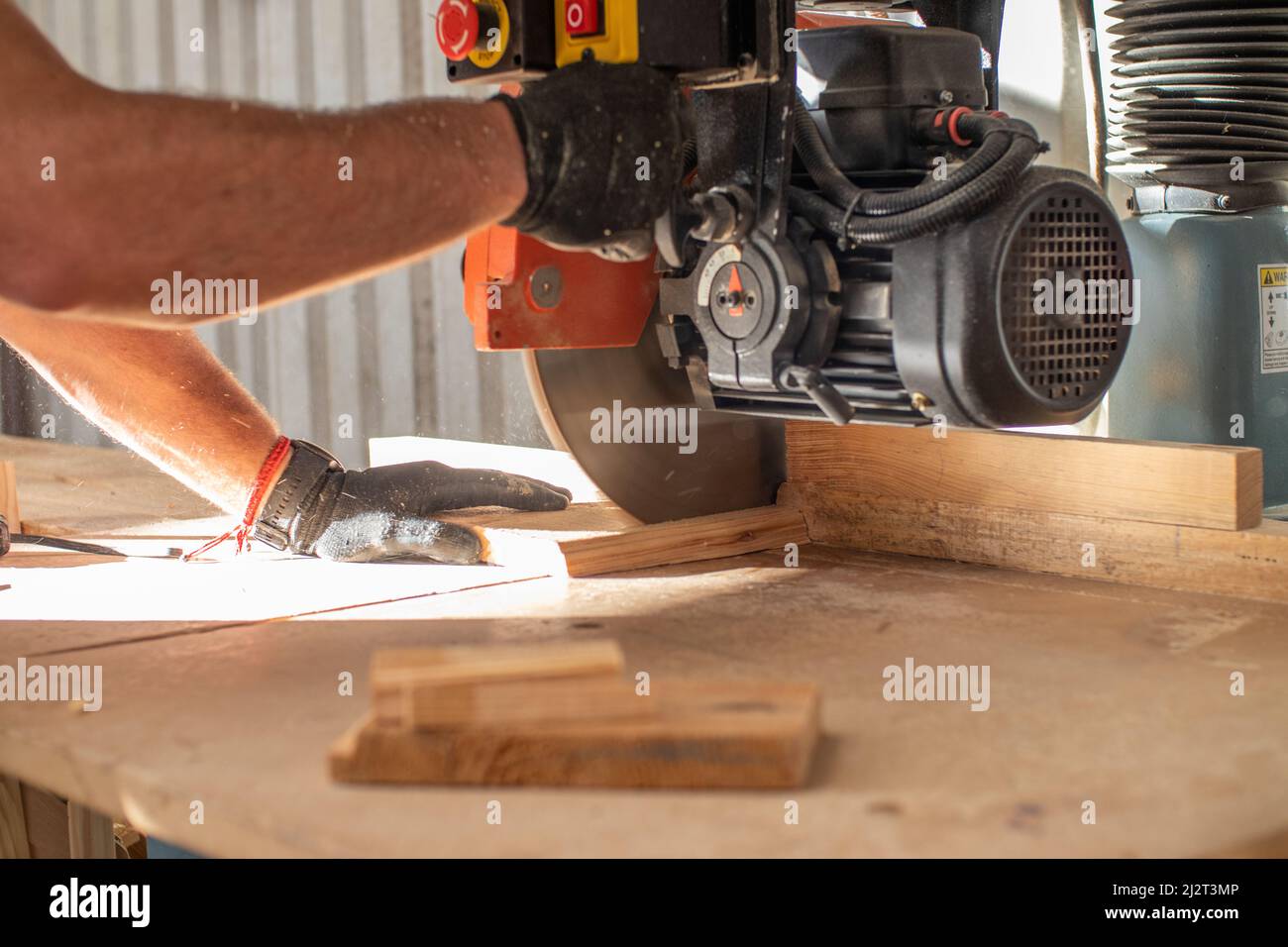hands of a young carpenter working on a circular saw machine cutting a