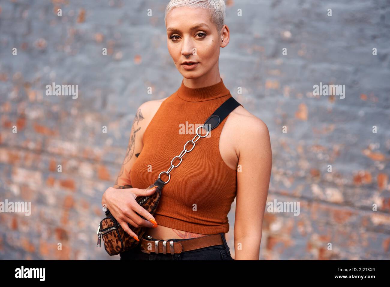 Confidence is my style. Cropped portrait of an attractive young woman looking serious while standing against a brick wall outdoors. Stock Photo