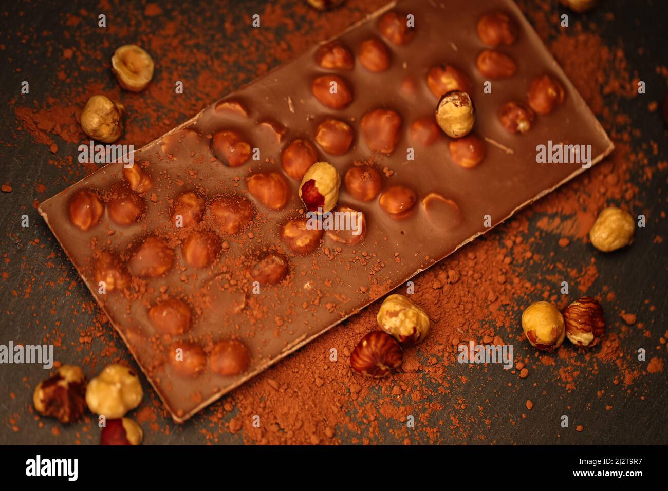 Chocolate bar.Chocolate with hazelnuts and cocoa powder on a slate background.Chocolate dessert with nuts.Bar of chocolate .Desserts and sweets Stock Photo