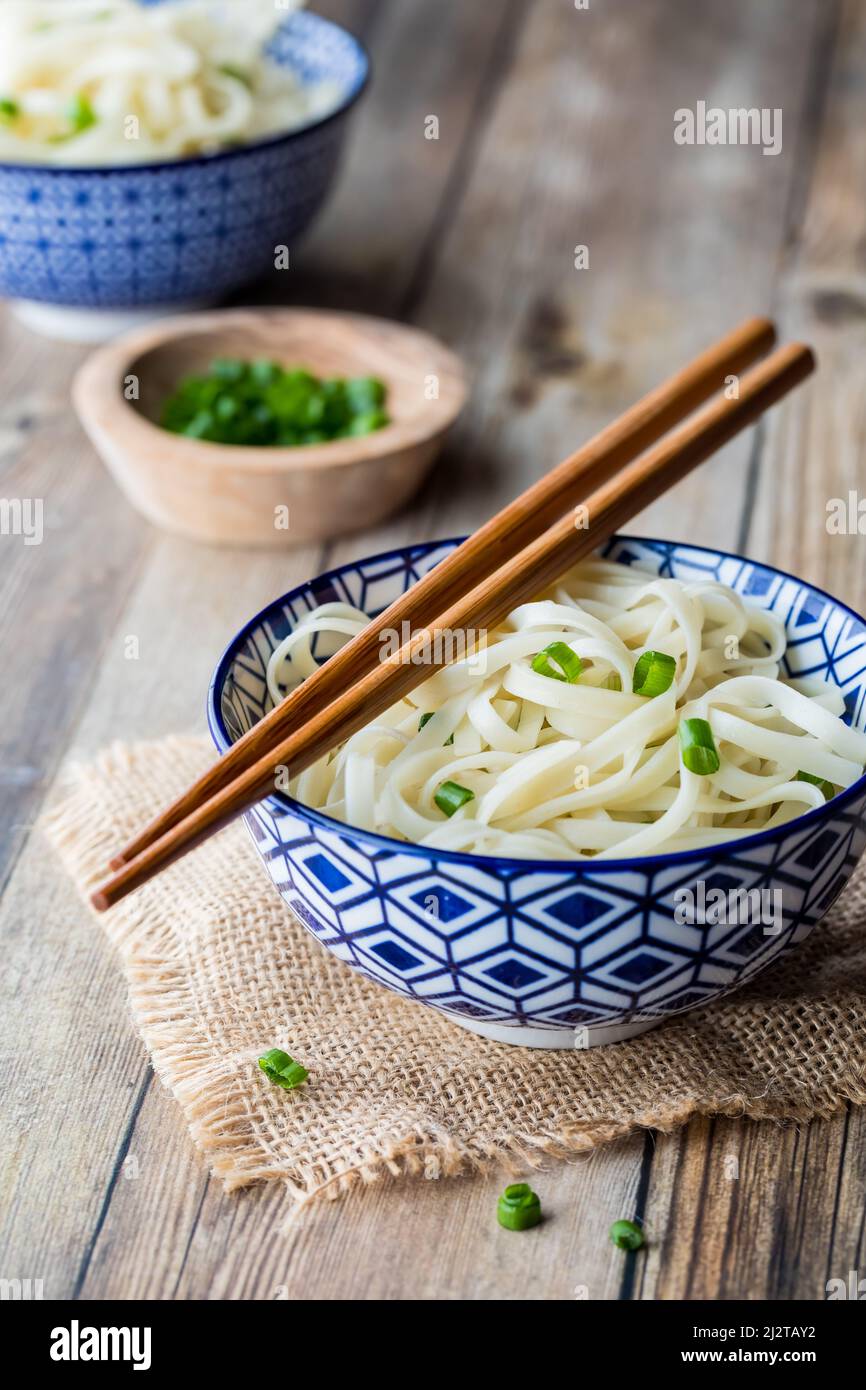 A decorative bowl filled with noodles and chopsticks resting on top. Stock Photo