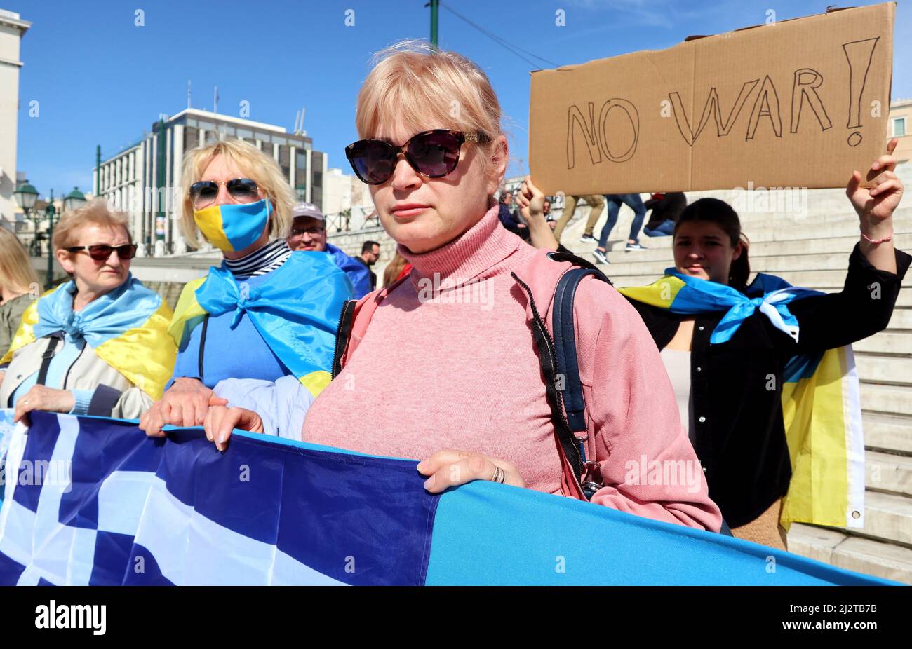 Refugee Tatiana, the woman in pink, stands at the Ukrainian community's protest against the war, Athens, Greece, April 3 2022. Tatiana fleed to Greece in March from bombed Kiev, with her daughter in law and grandchildren. A hundred Ukrainian people gathered outside of the Greek Parliament to ask the end of the war and condemn Russian aggression. At the same time, dozens of cars with Russian flags paraded along the streets near the Parliament. Greek police controlled the area and faced the demonstrators until the end of the protest. (Photo by Elisa Gestri/ Sipa USA) Stock Photo