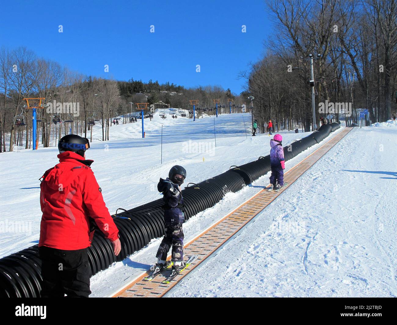 Family of skiers on a magic carpet on a ski hill Stock Photo