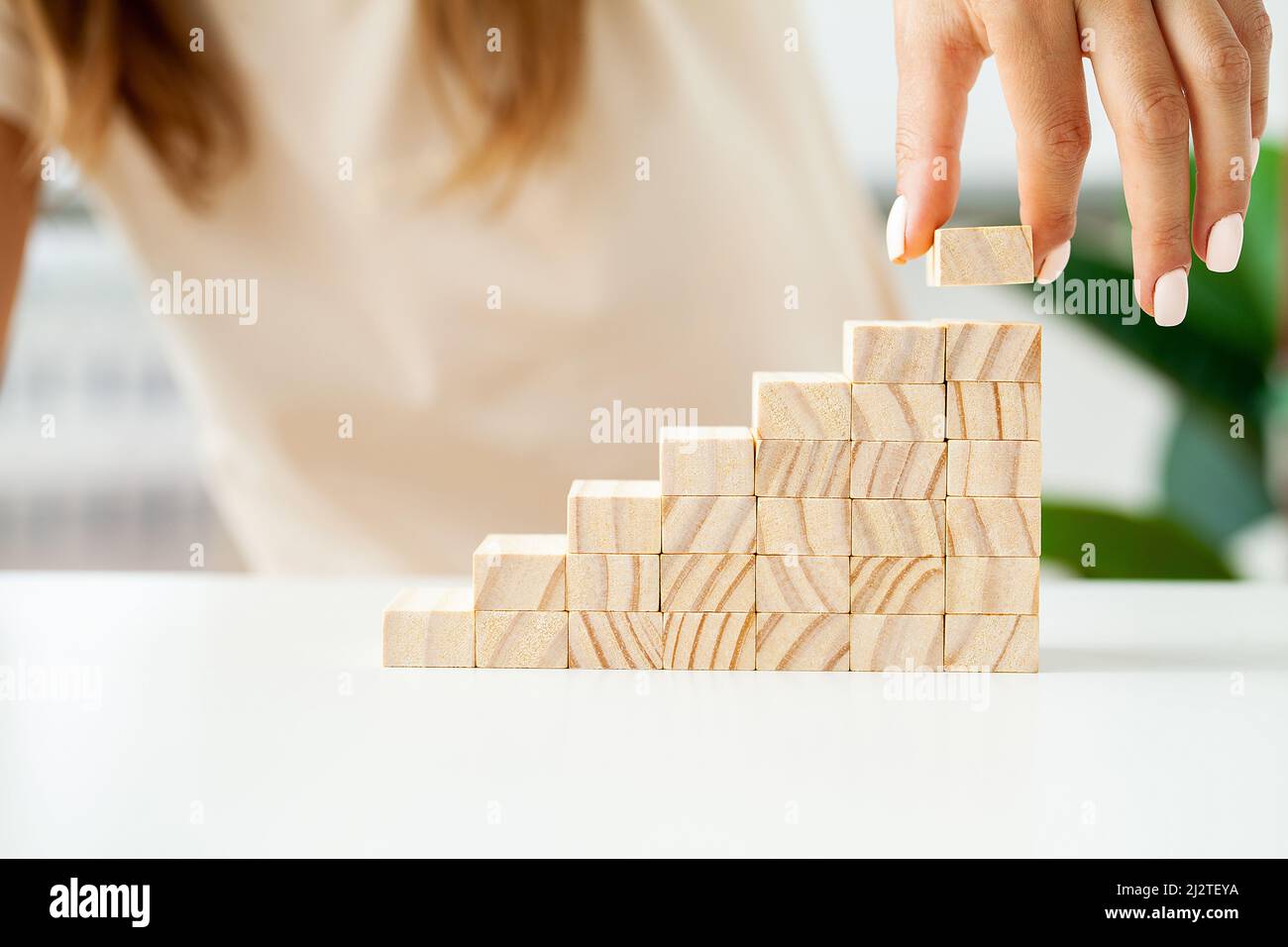 Woman hand stacking wooden blocks in shape of staircase Stock Photo - Alamy