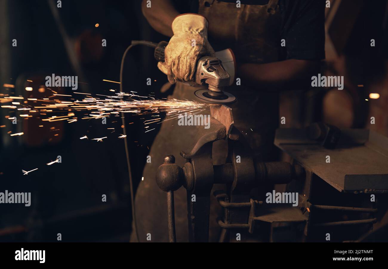 To make art, youve got to make a spark. Shot of a man using an angle grinder while working at a foundry. Stock Photo