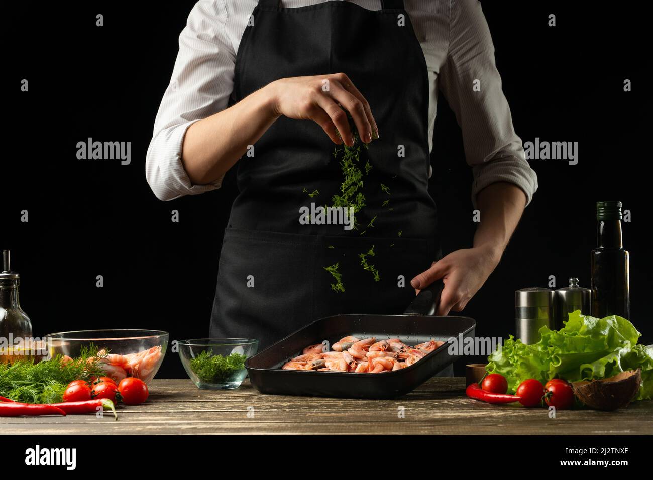 Professional chef sprinkles shrimps for salad, seafood and healthy food ...