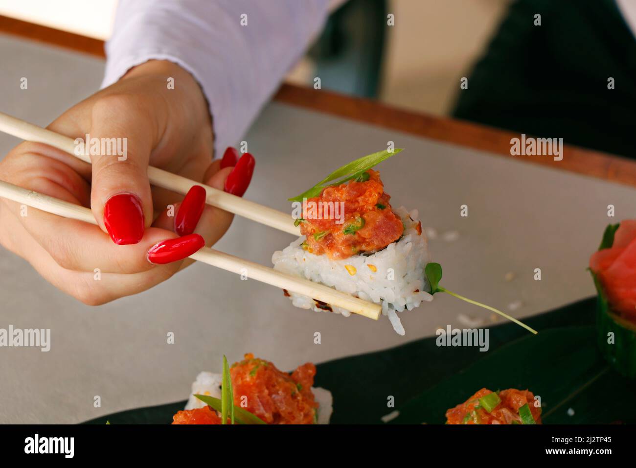 Sushi Roll on a black plate with woman hand holding chopsticks, japanese food Stock Photo