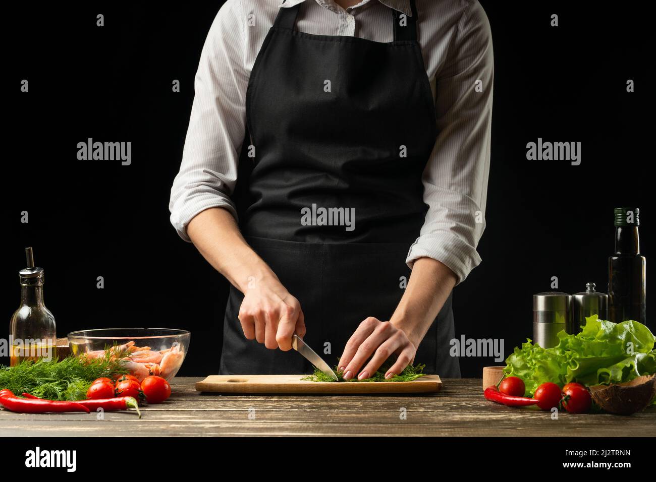 Professional chef cuts greens for salad with shrimps, the concept of ...