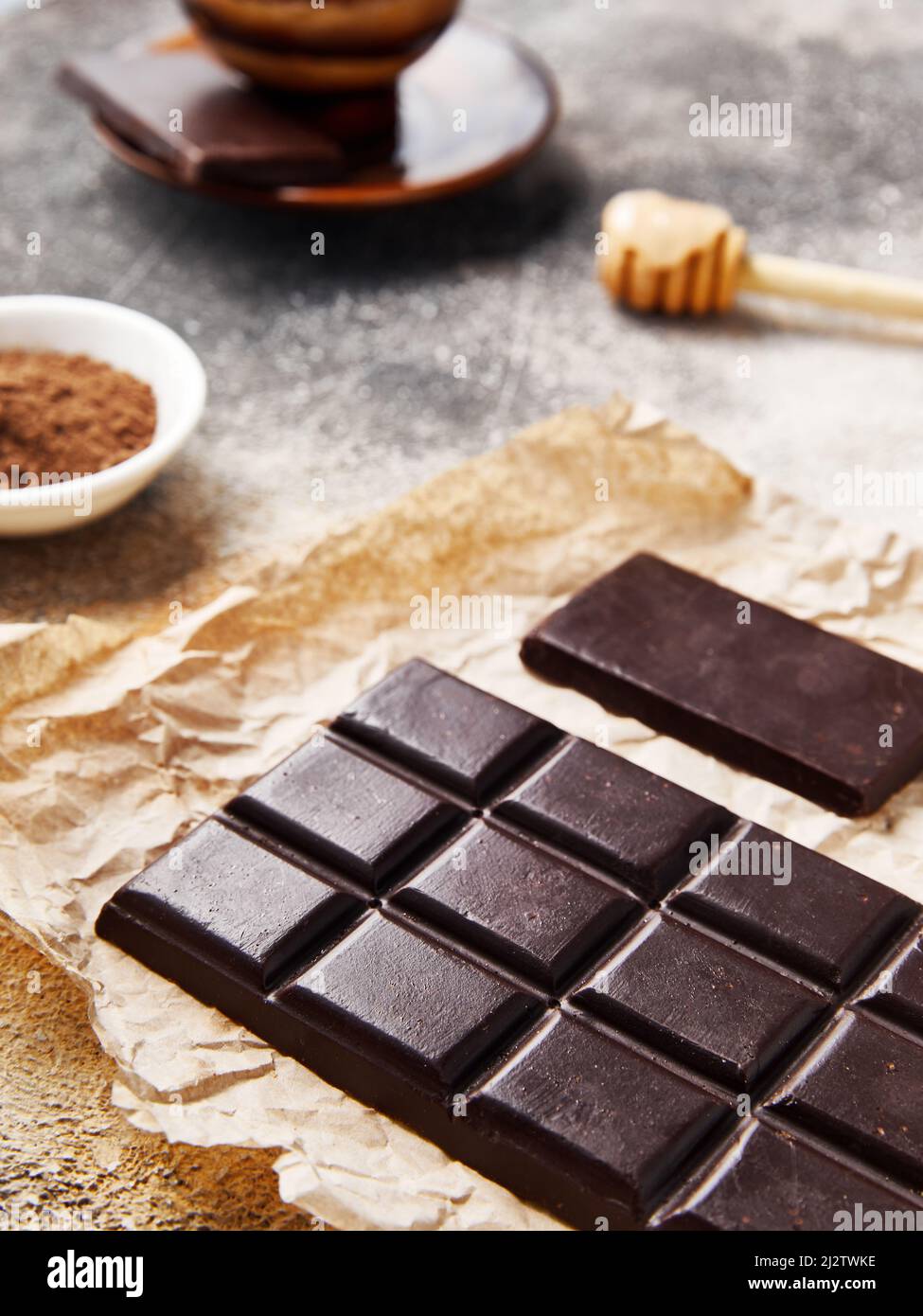 Healthy Sugar free Homemade raw chocolate with cocoa and honey on craft paper. Big and small bars. Cup of coffee nearby Stock Photo