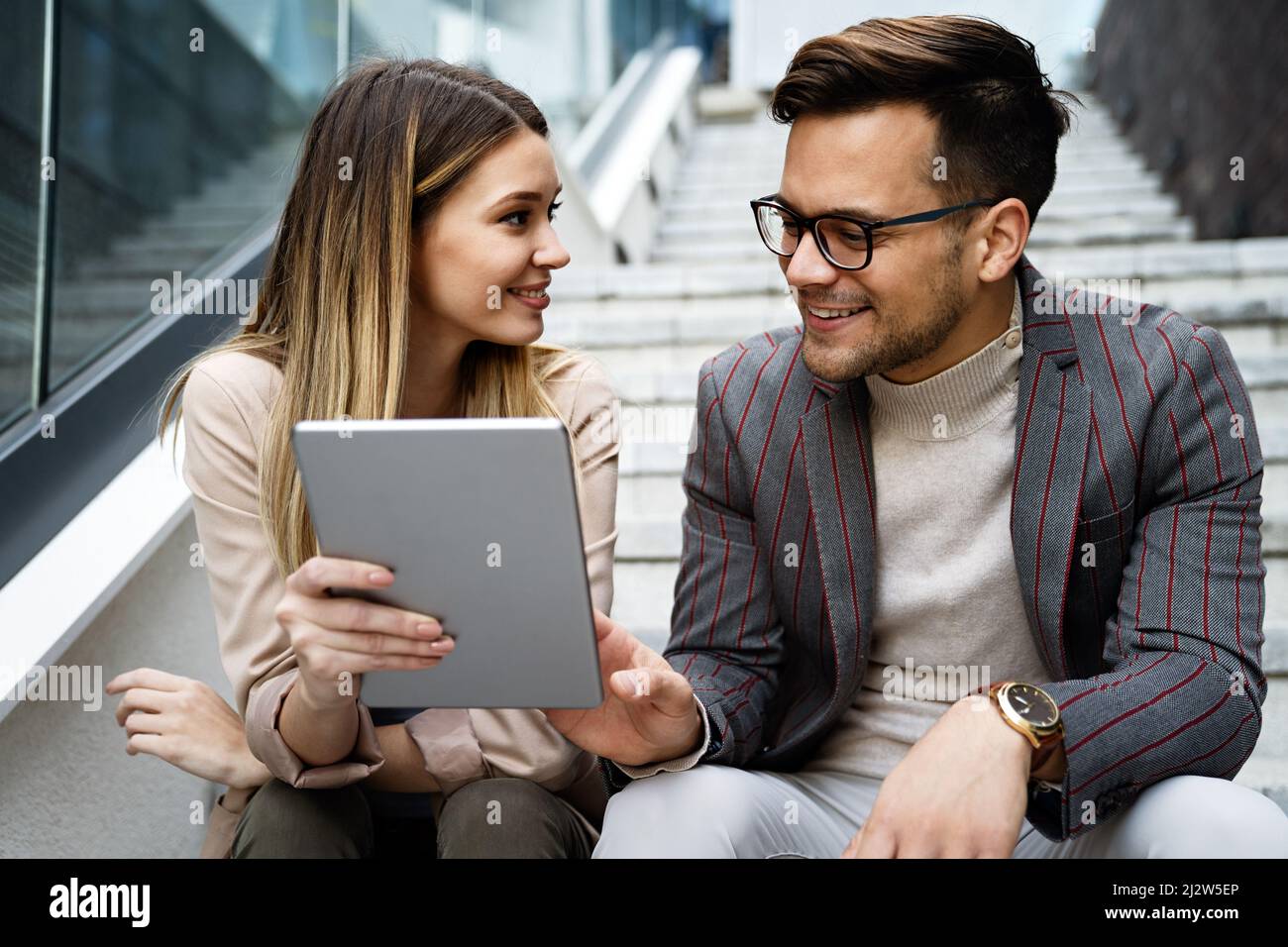 Successful young business people talking, working together in front of modern business building Stock Photo