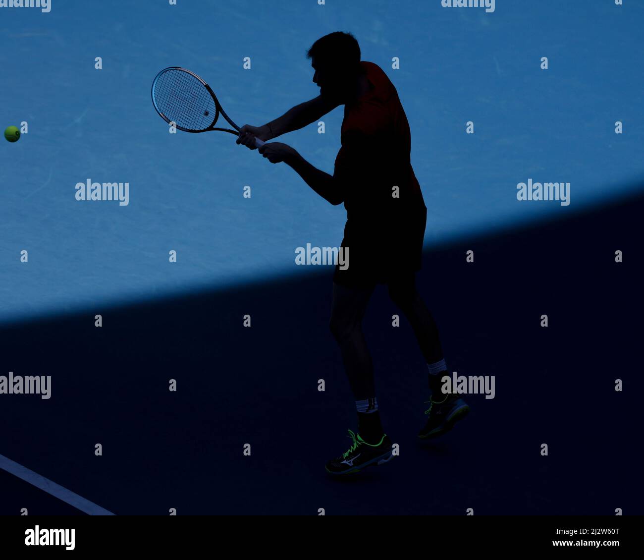 Silhouette of German tennis player Mats Moraing playing a backhand shot during  the Australian Open 2022 tennis tournament, Melbourne Park, Melbourne, Stock Photo