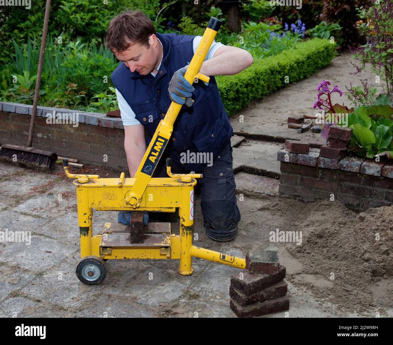Netherlands - Construction worker cutting tile or stone brick with a special tile cutting machine. Stock Photo