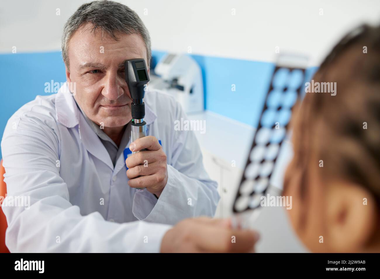 Senior experienced ophthalmologist using retinoscopy and retinoscopy rack during eyes