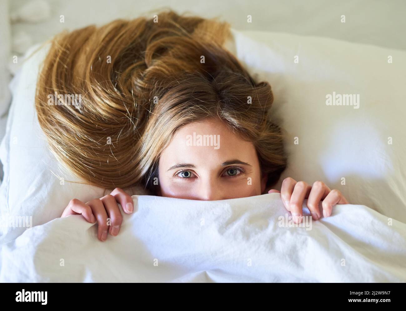 Theres no way Im leaving this bed today. Portrait of a playful young woman hiding under the