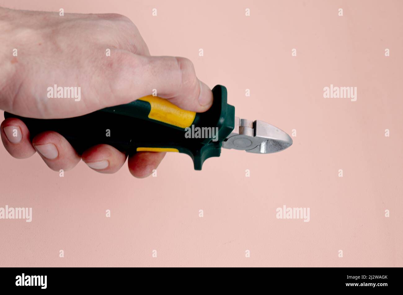 side cutters in hands on a light pink background Stock Photo
