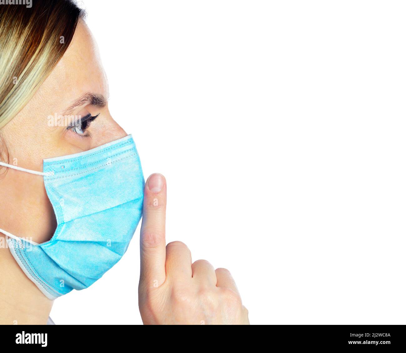 Woman wearing a face mask with her finger on her lips, keeping a secret or asking for silence Stock Photo