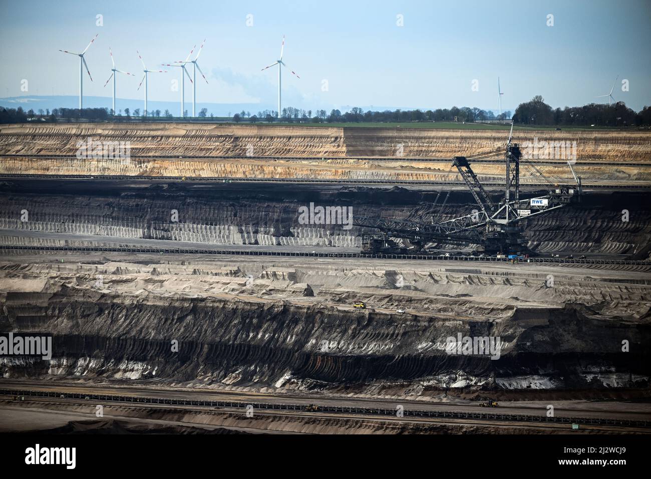 Jackerath, Germany. 04th Apr, 2022. Mining machines work in the Garzweiler open pit lignite mine, with wind turbines in the background. Today, the Intergovernmental Panel on Climate Change will present a comprehensive overview of how man-made climate change can be limited. The report reflects the current state of research on what measures are necessary and effective to curb global warming and avert climate catastrophe. Credit: Federico Gambarini/dpa/Alamy Live News Stock Photo