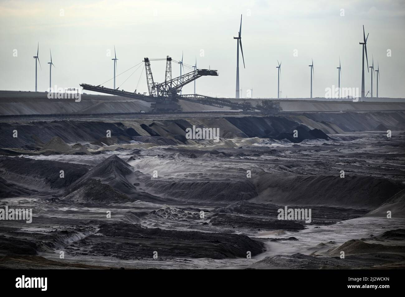 Jackerath, Germany. 04th Apr, 2022. Mining machines work in the Garzweiler open pit lignite mine, with wind turbines in the background. Today, the Intergovernmental Panel on Climate Change will present a comprehensive overview of how man-made climate change can be limited. The report reflects the current state of research on what measures are necessary and effective to curb global warming and avert climate catastrophe. Credit: Federico Gambarini/dpa/Alamy Live News Stock Photo
