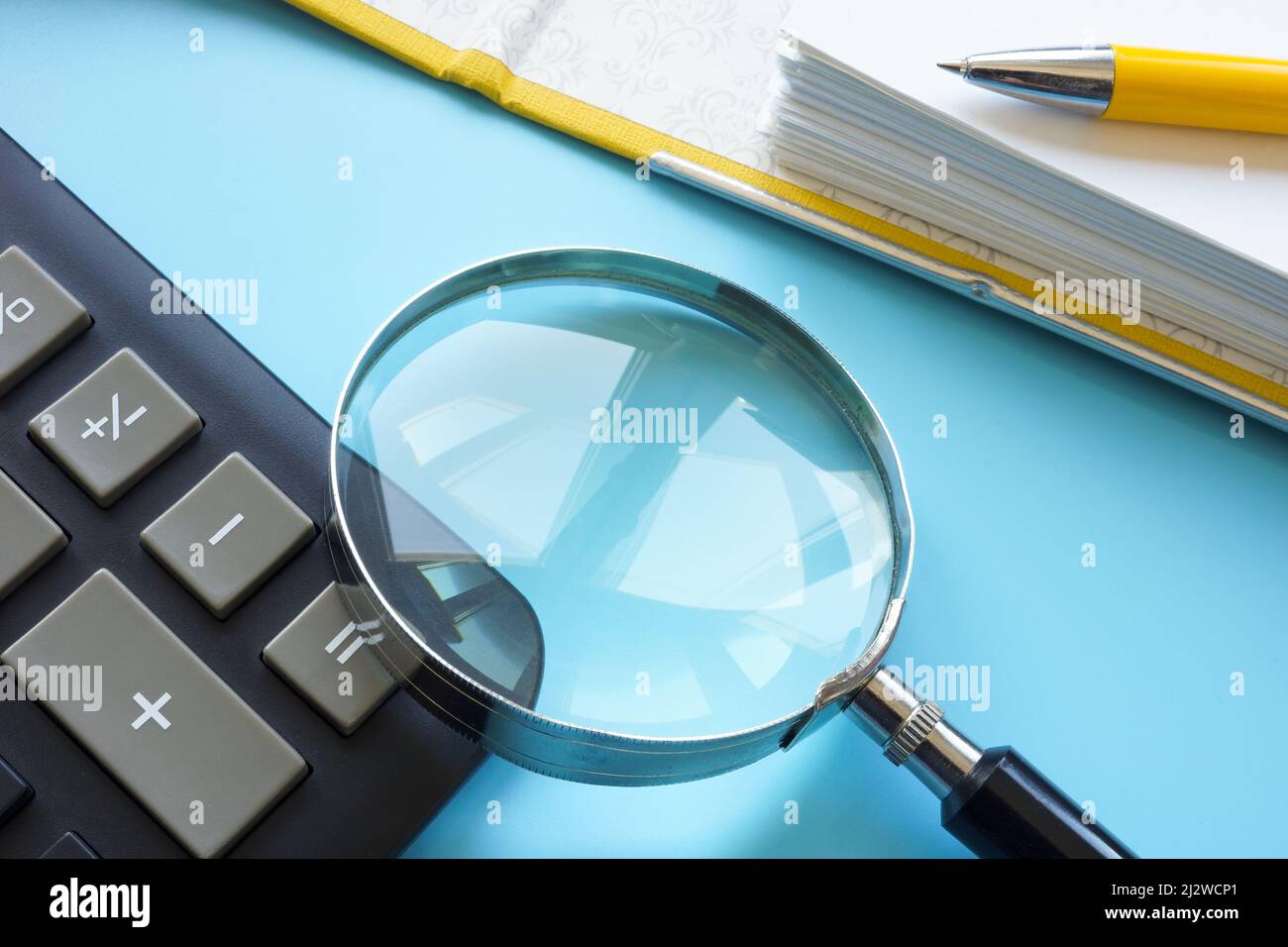 A magnifying glass as a symbol of audit lies on a table with documents. Stock Photo