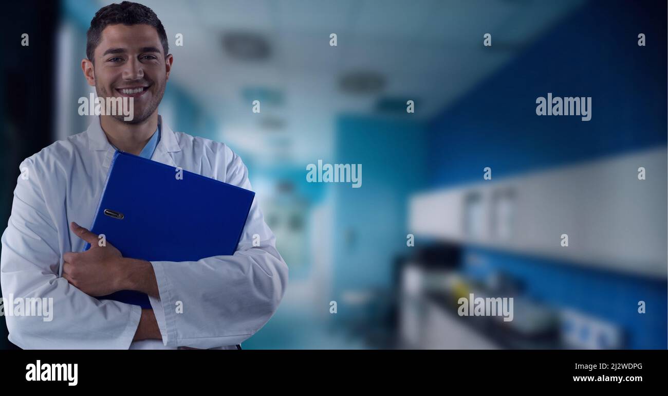 Smiling doctor with hospital hallway in the background, healthcare and medical professional concepts Stock Photo