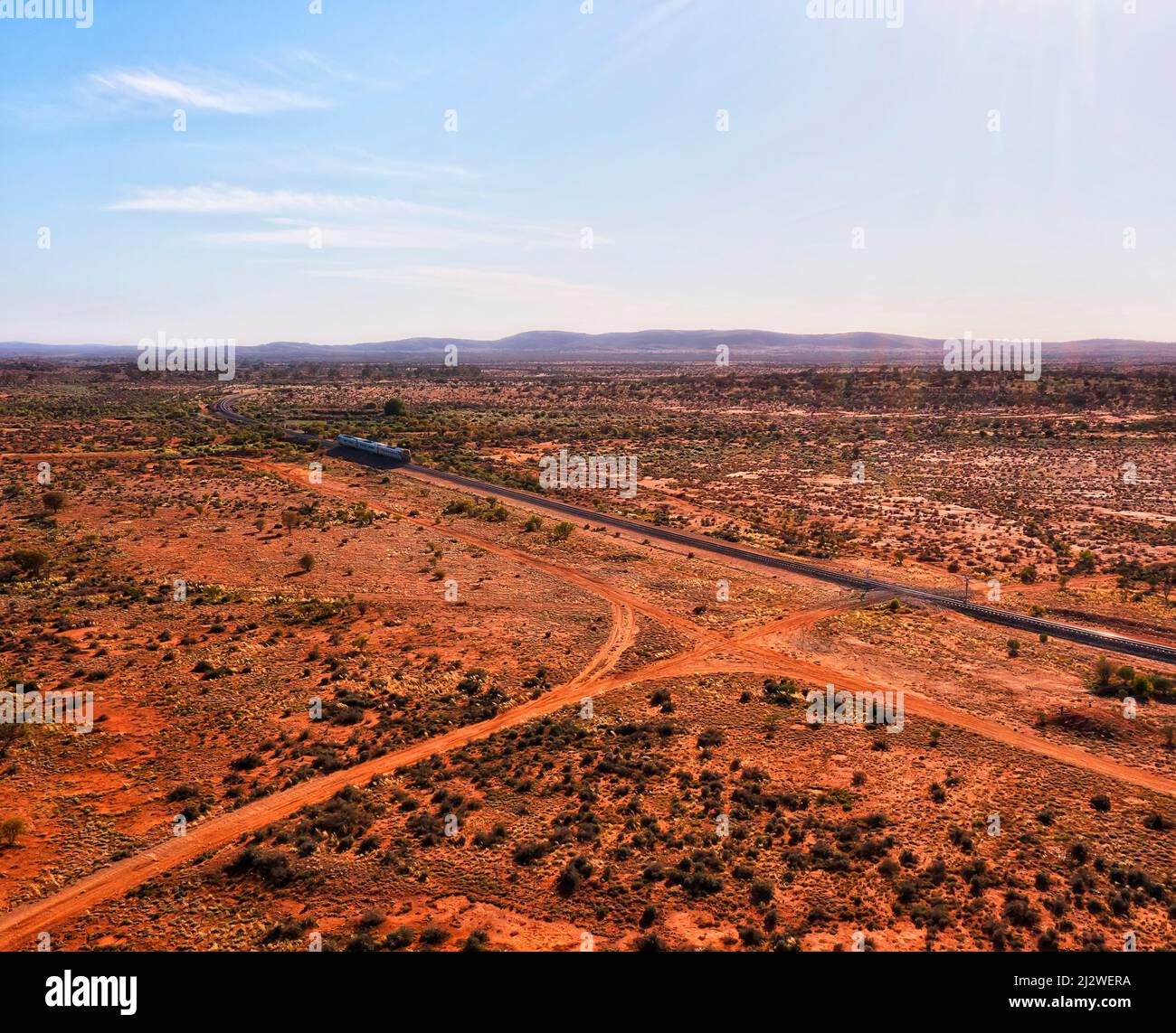 Broken Hill - Sydney passenger train en route through Australian outback with red soil - aerial landscape. Stock Photo