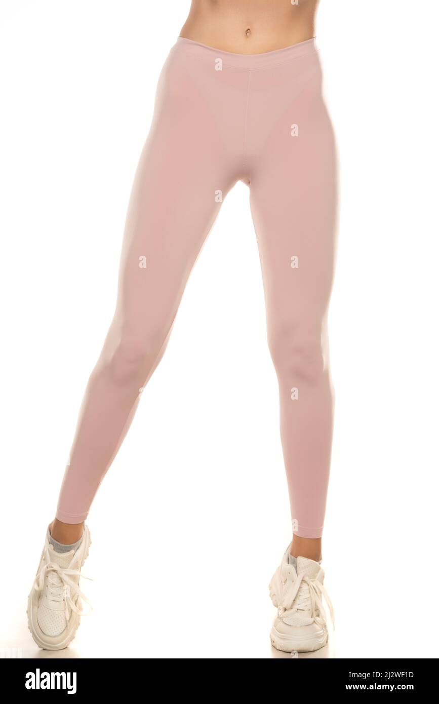Front view of a female legs in sport pink tights and sneakers on white background. Stock Photo