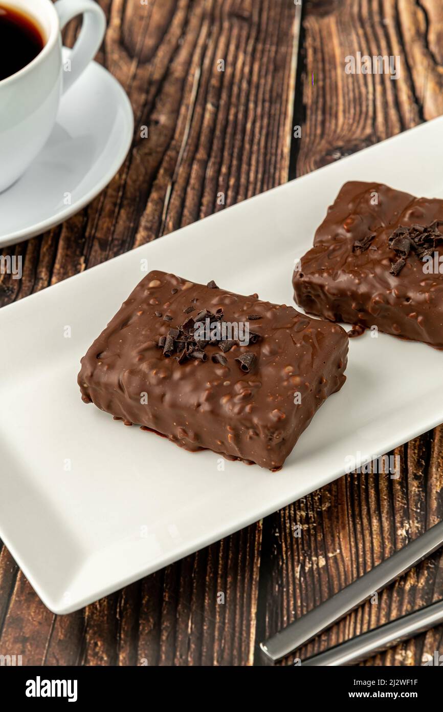 Chocolate covered raisin cake on wooden table with filter coffee Stock Photo